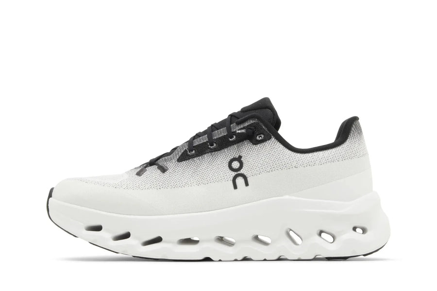 Tênis On Running Cloudtilt 'Black Ivory' Branco em fundo branco, detalhes de design e sola perfurada.